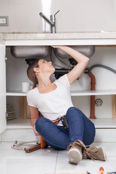 Plumber woman fixing the pipe of the kitchen