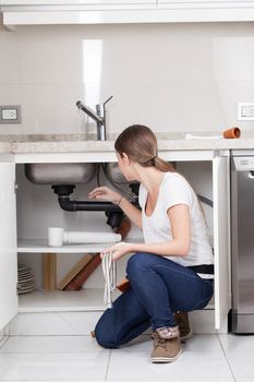 Woman repairing the pipe of the kitchen