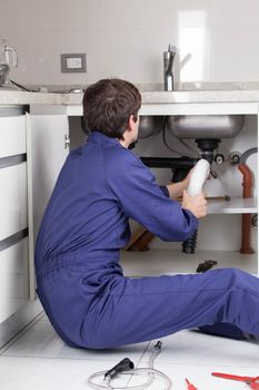 Man fixing a pipe sitting on the floor