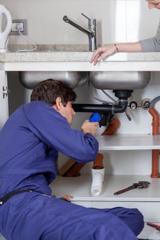 Plumber looking at the plumbing with his flashlight