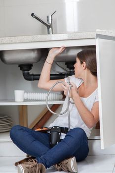 Plumber woman fixing the pipe of the kitchen