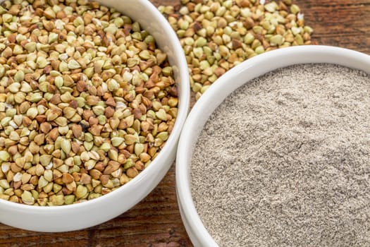 gluten free buckwheat grain and flour - top view of two ceramic bowls against rustic wood