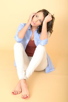 Sad Unhappy Worried Attractive Beautiful Young Woman Sitting on the Floor Wearing a Blue Shirt and White Jeans