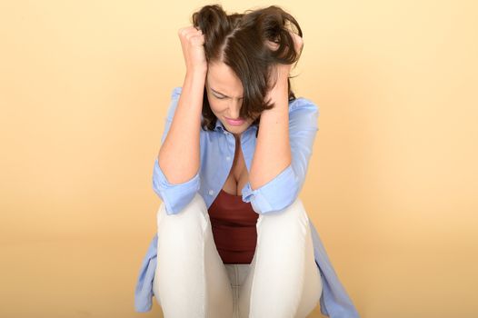 Attractive Beautiful Sad Depressed and Angry Young Woman Sitting on the Floor Wearing a Blue Shirt and White Jeans 