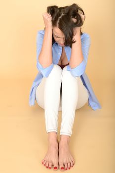 Attractive Beautiful Sad Depressed and Angry Young Woman Sitting on the Floor Wearing a Blue Shirt and White Jeans 