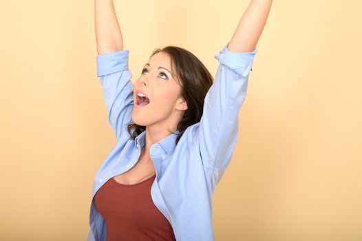 Attractive Young Woman Sitting on the Floor Wearing a Blue Shirt and White Jeans Raising Her Hands in Excitement