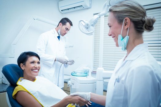 Female dentist shaking hands with woman in the dentists chair