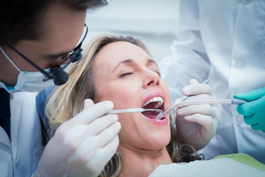 Close up of woman having her teeth examined by dentist and assistant