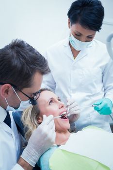 Close up of male dentist with assistant examining womans teeth in the dentists chair