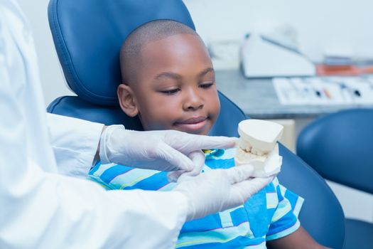 Cropped dentist showing young boy prosthesis teeth in the dentists chair