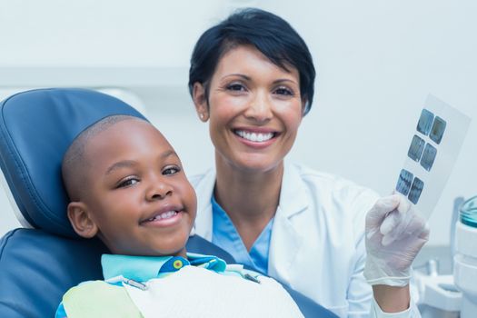 Female dentist showing young boy his mouth x-ray in the dentists chair