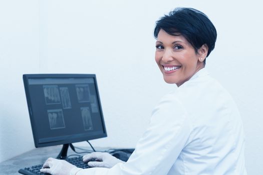 Portrait of smiling female dentist with x-ray on computer
