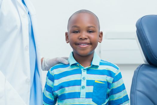 Portrait of smiling young boy standing by cropped dentist