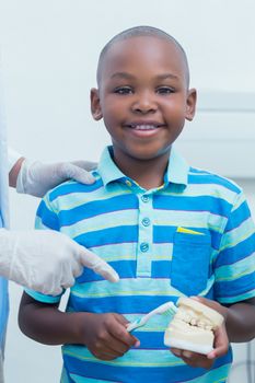 Cropped dentist teaching young boy how to brush teeth