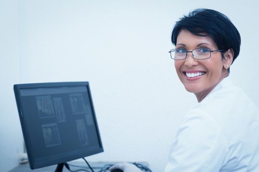 Portrait of smiling female dentist with x-ray on computer