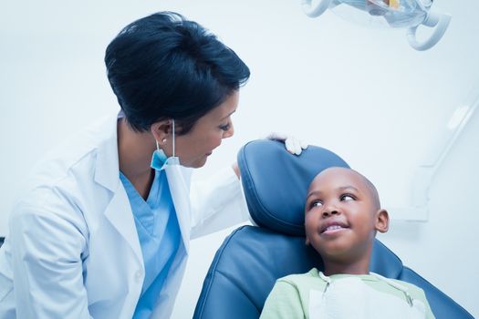 Female dentist examining boys teeth in the dentists chair