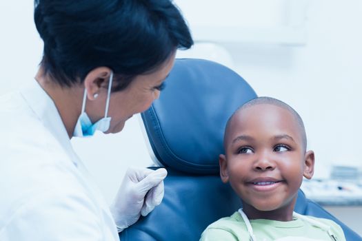 Female dentist examining boys teeth in the dentists chair