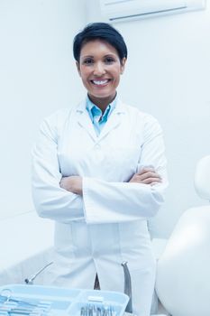 Portrait of smiling female dentist standing with arms crossed