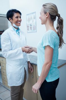 Side view of female dentist shaking hands with woman