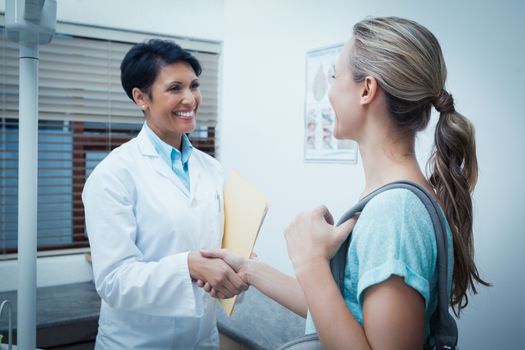 Side view of female dentist shaking hands with woman