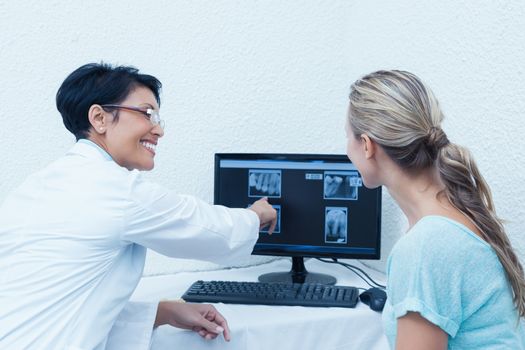 Side view of female dentist showing woman her mouth x-ray on computer