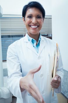 Portrait of smiling female dentist offering a handshake