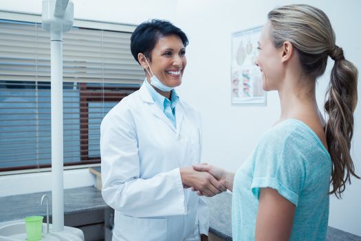 Side view of female dentist shaking hands with woman