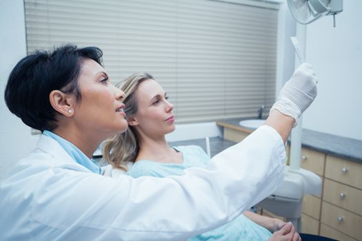 Side view of female dentist showing woman her mouth x-ray