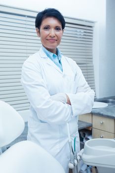 Portrait of smiling female dentist standing with arms crossed