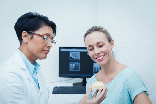 Female dentist showing happy woman prosthesis teeth