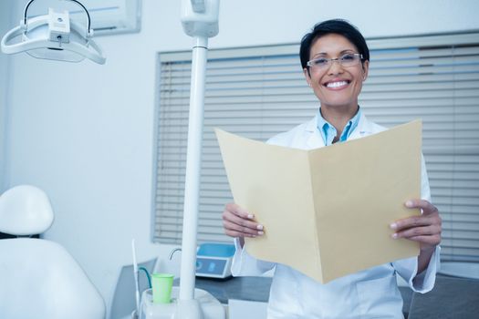 Portrait of smiling female dentist reading reports