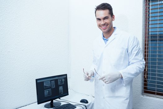 Portrait of smiling male dentist with computer monitor