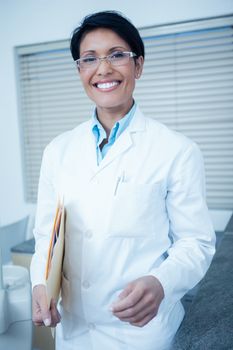 Portrait of smiling young female dentist holding folder