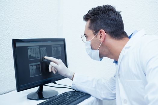 Concentrated male dentist looking at x-ray on computer