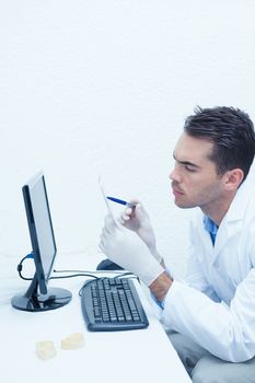 Concentrated male dentist looking at x-ray by computer