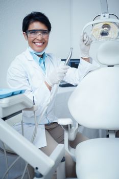 Portrait of smiling young female dentist holding dental tool