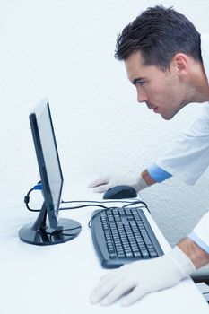 Side view of concentrated male dentist looking at computer monitor