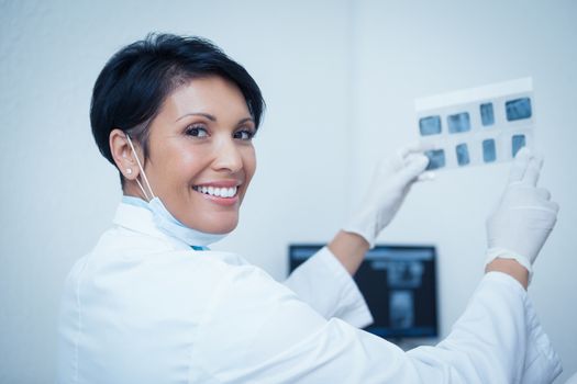Portrait of smiling young female dentist holding x-ray