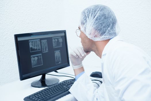 Concentrated male dentist looking at x-ray on computer