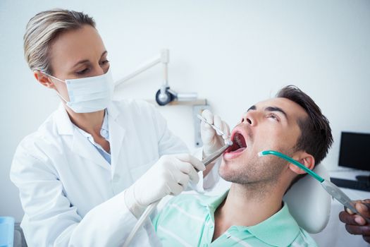 Female dentist examining mans teeth in the dentists chair