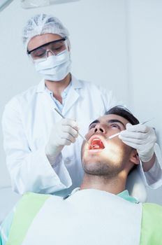 Female dentist examining mans teeth in the dentists chair