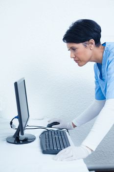 Side view of concentrated female dentist looking at computer monitor