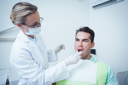 Female dentist examining mans teeth in the dentists chair