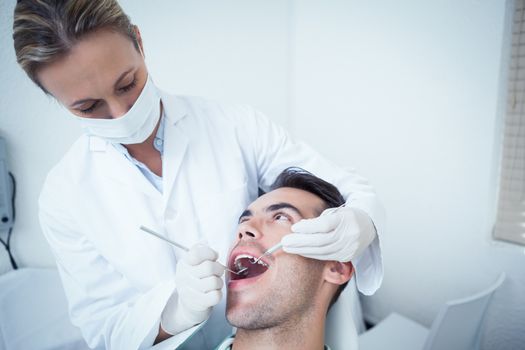 Female dentist examining mans teeth in the dentists chair