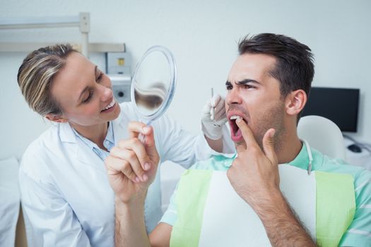 Young man looking at mirror in the dentists chair