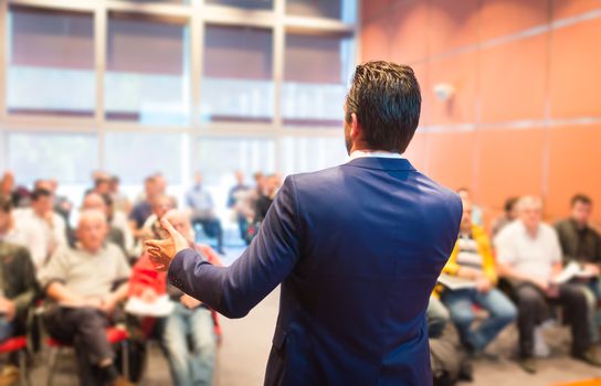 Speaker at Business Conference with Public Presentations. Audience at the conference hall. Entrepreneurship club. Rear view. Horisontal composition. Background blur.