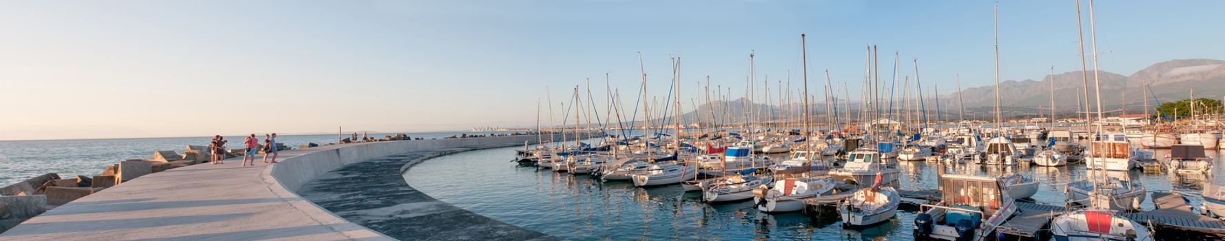 CAPE TOWN, SOUTH AFRICA - DECEMBER 11, 2014:  Sunset panorama of the harbor in Gordons Bay with buildings of Gordons Bay and The Strand in the background