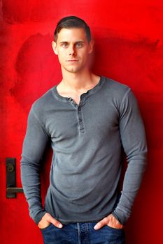 Portrait of a man standing in front of a red door.