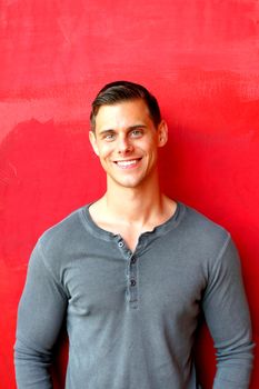 Portrait of a man standing in front of a red wall.