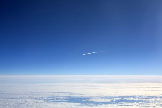 High Altitude Aircraft Lonely Vapour Trail Against a Blue Sky Above The Clouds